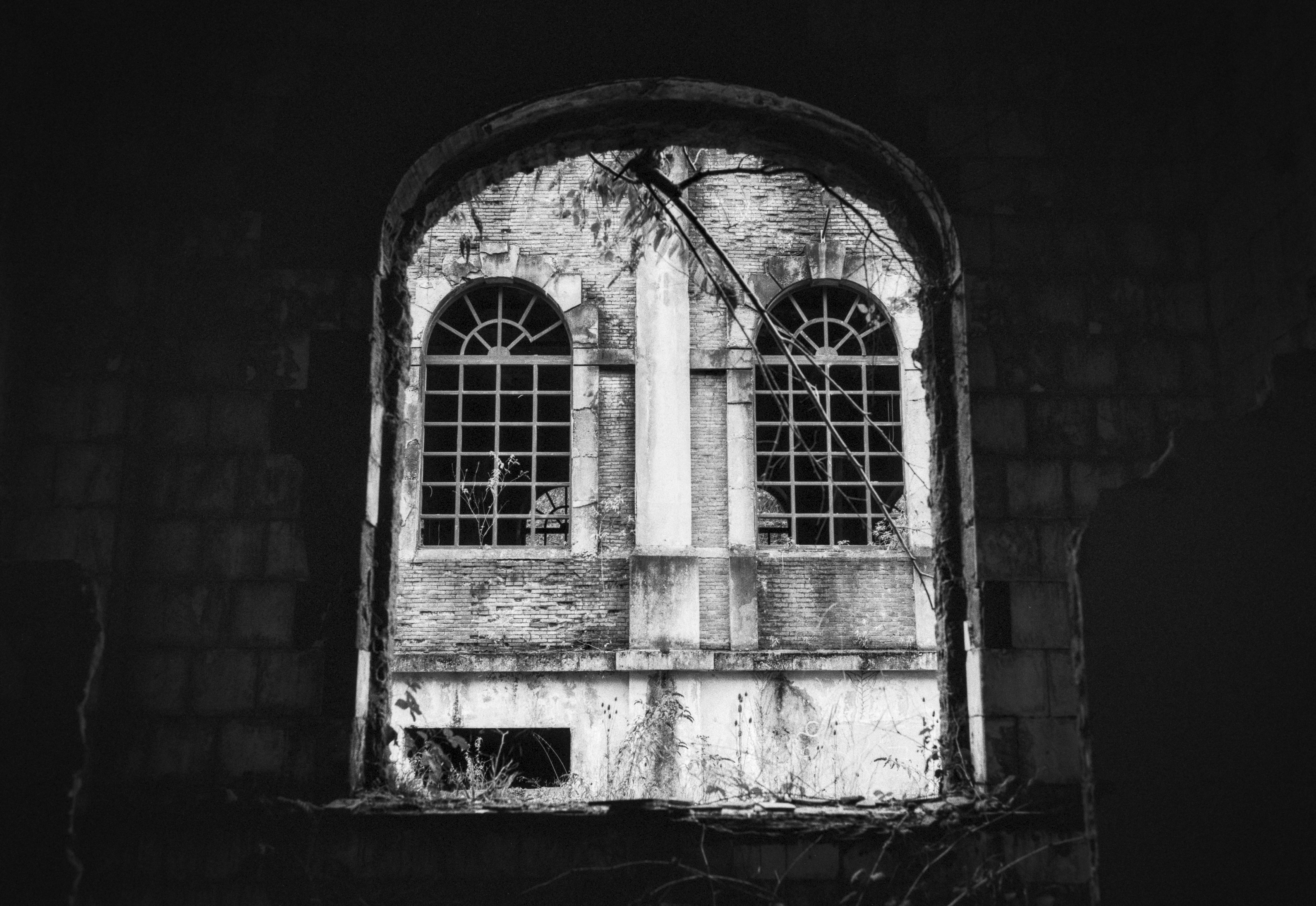 Ruined industrial building seen through a large arched opening.