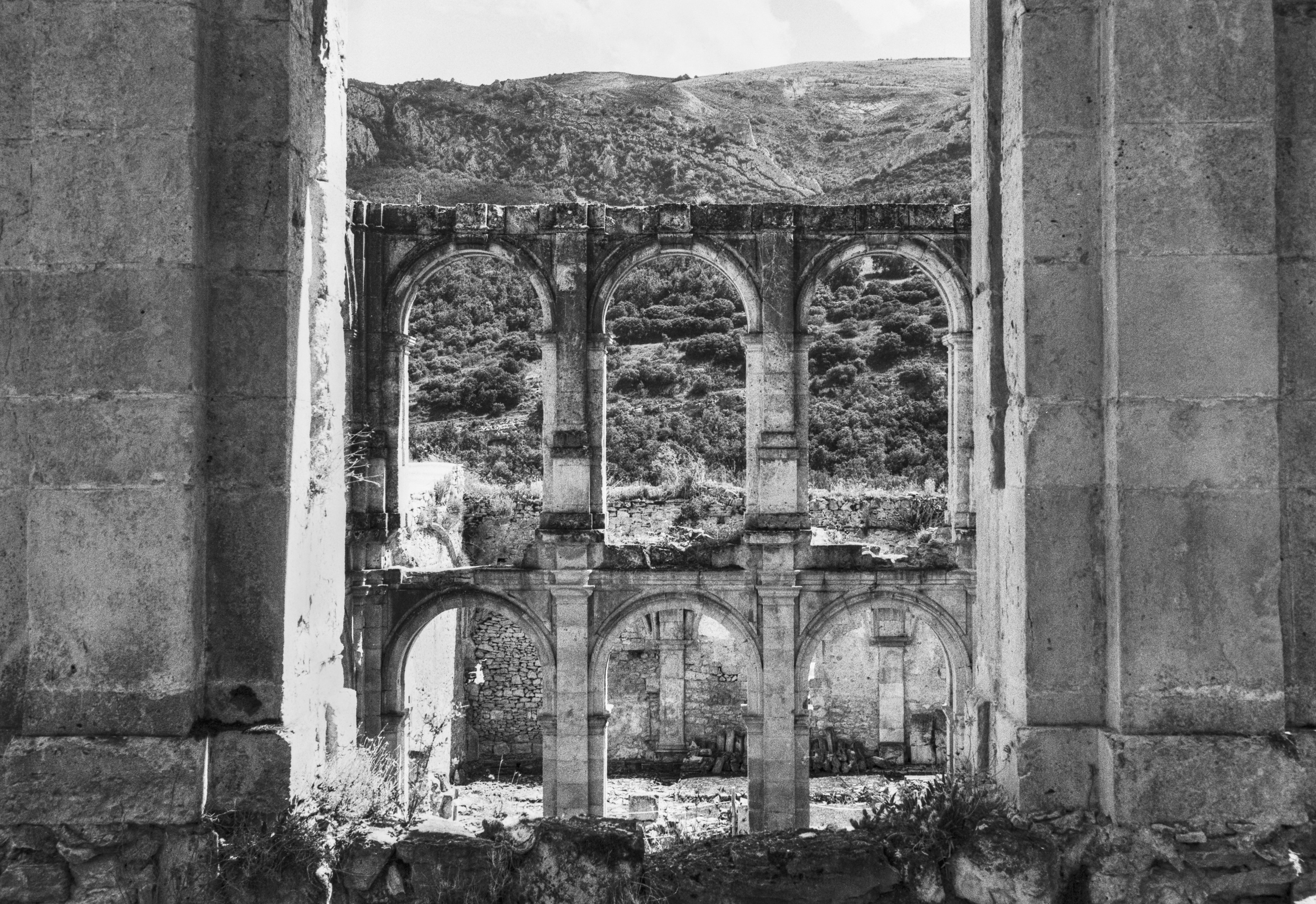 Arched stone walls of the Monastery of Santa María de Rioseco framed between two pillars.